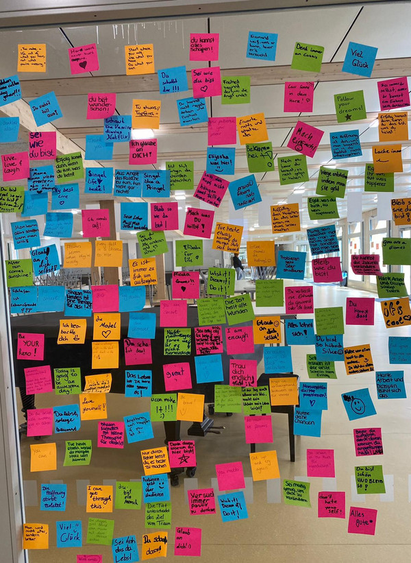 Post-it's mit motivierenden Worten an der Glaswand im Foyer